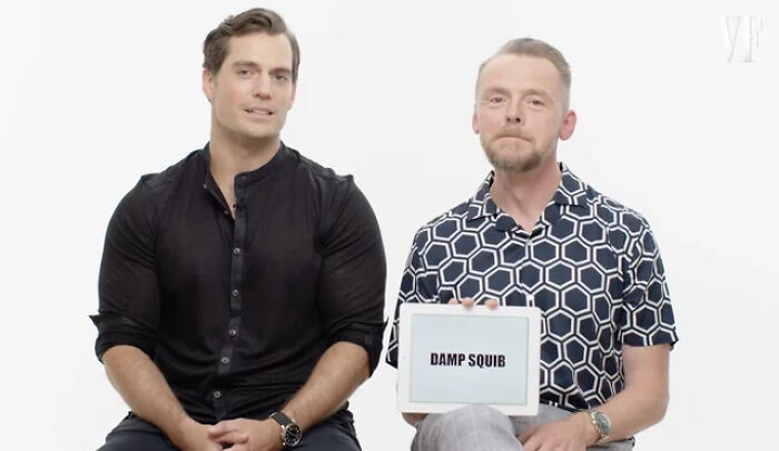 Henry Cavill and Simon Pegg, featuring dry British humor, holding a sign that says Damp Squib.