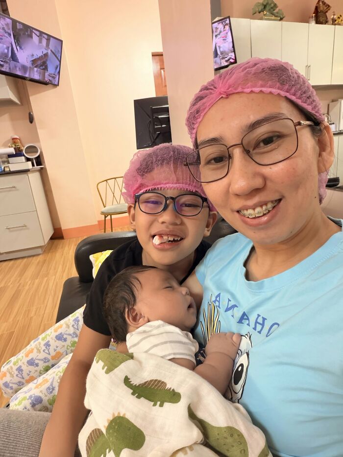 A mom with two children, one an infant, all wearing hairnets, showing that motherhood is rewarding and joyful.