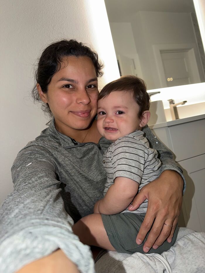 A happy mom holding her baby, both looking at the camera; the joys of motherhood are evident.