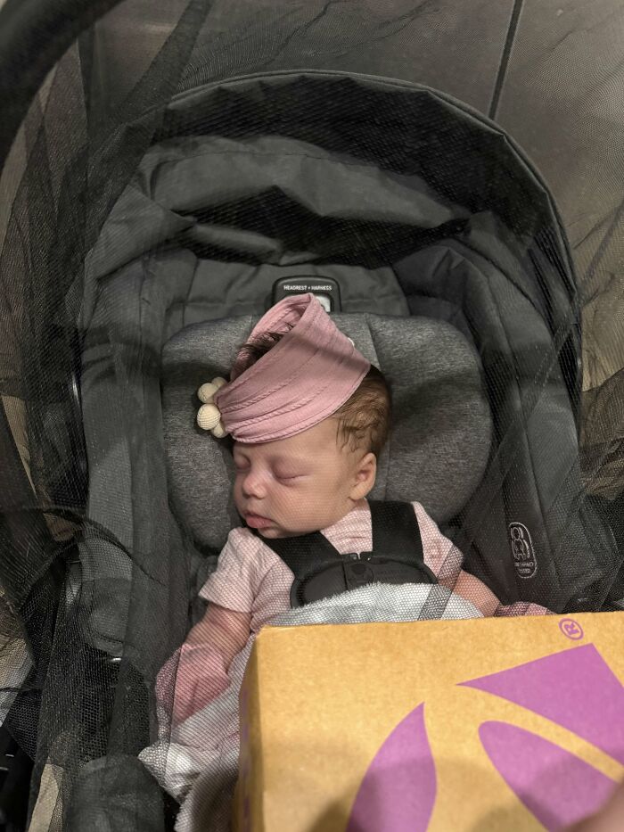 A baby in a car seat with a pink hat sleeps peacefully, a common sight for moms experiencing the rewarding journey of motherhood.