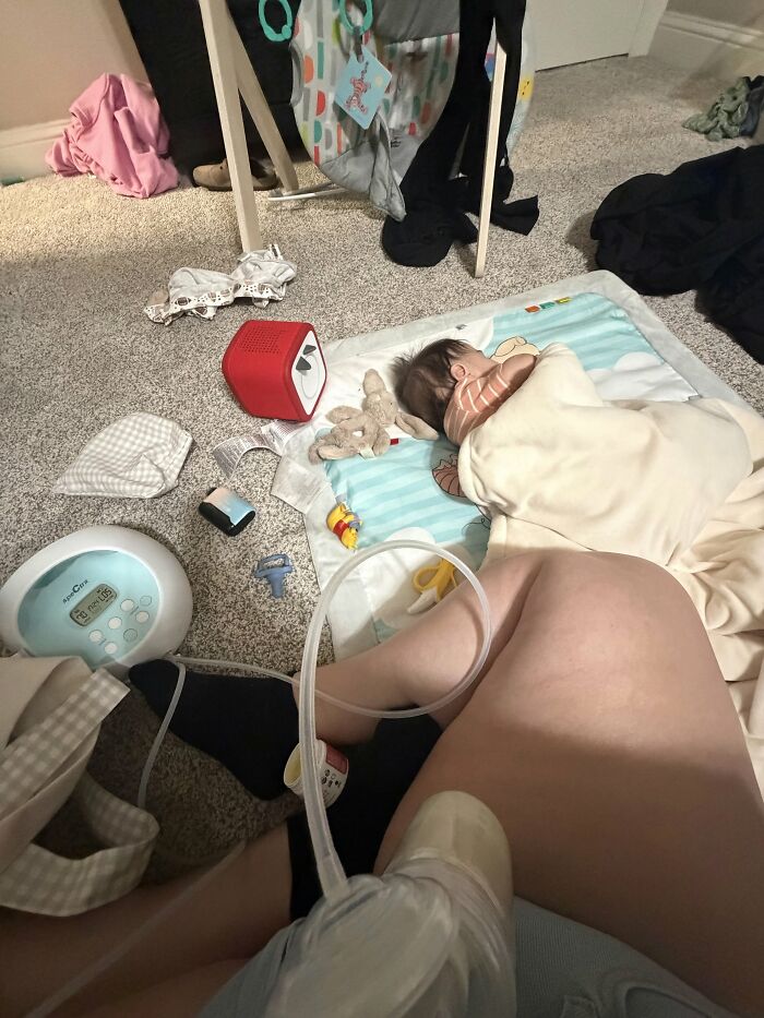 A mom using a breast pump while her baby sleeps on a mat, emphasizing the rewarding and challenging journey of motherhood.
