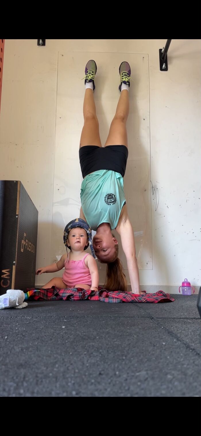 A mom doing a handstand next to her baby, demonstrating the fulfilling and joyful experience of motherhood.