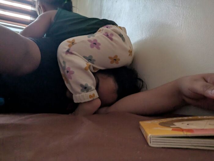 Motherhood is rewarding: A toddler climbs on a parent trying to rest, showcasing the demanding yet joyful life.