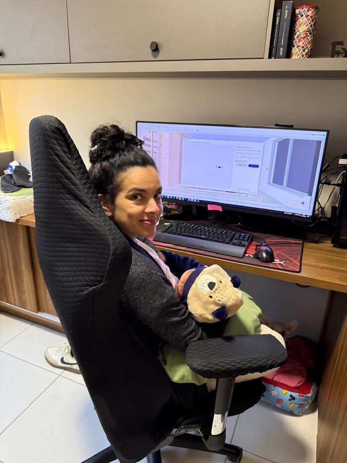 Motherhood is rewarding: A smiling mom at her desk with a baby on her lap, showing a joyful and fulfilling aspect.