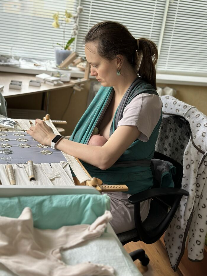 A mother breastfeeding her baby while working at a desk, illustrating that motherhood is rewarding but not easy.
