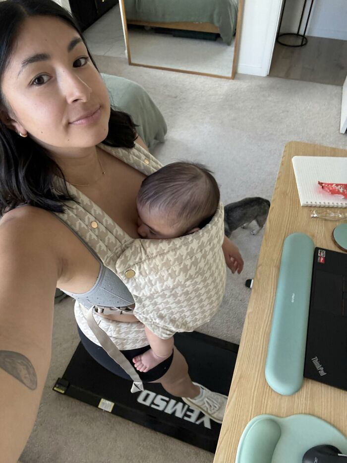 A mom with a baby in a carrier, exercising on a treadmill, highlighting the joyful and fulfilling aspects of motherhood.