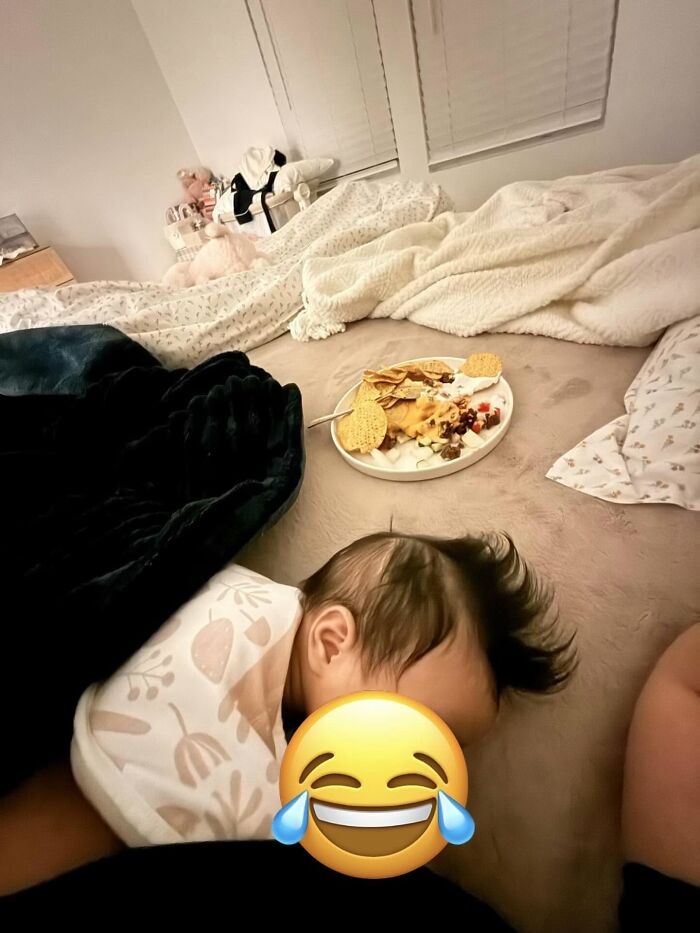 A baby sleeping soundly on a bed with a plate of snacks nearby, showcasing the rewarding side of motherhood.