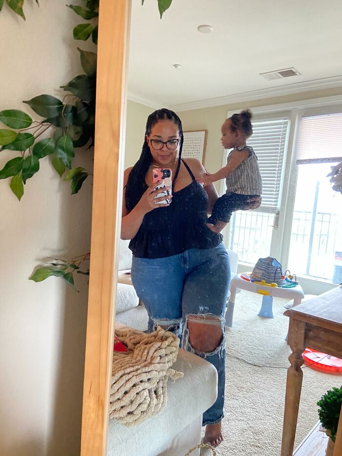 A mom takes a mirror selfie while holding her toddler, showing a real-life moment of motherhood.