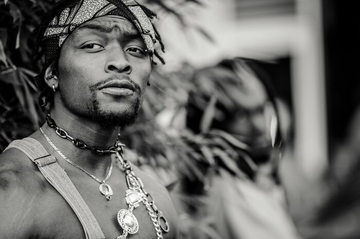 A man with dreadlocks and a bandana wearing layered necklaces, a firsthand witness to absurd and hilarious things.