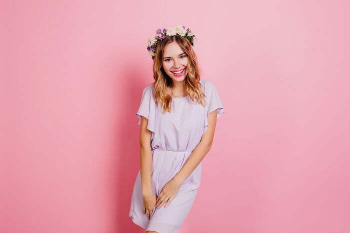 A young woman in a purple dress and flower crown smiles. A firsthand witnessed moment of absurd and hilarious joy.
