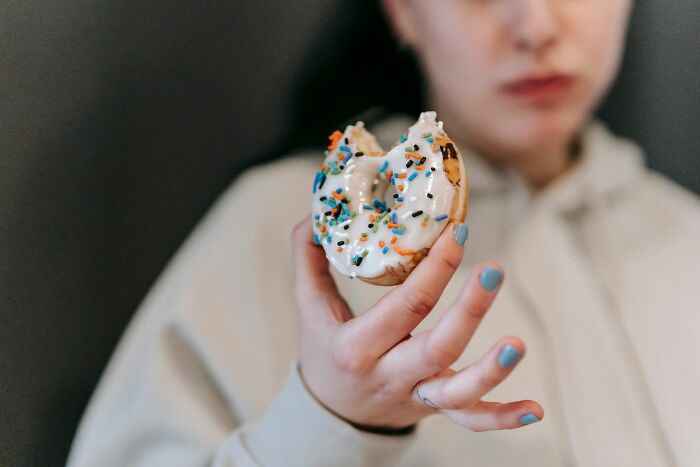 A person holding a half-eaten donut with sprinkles, one of the absurd and hilarious things folks have witnessed.