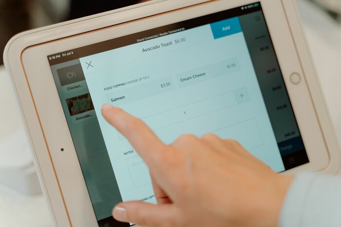 A hand selecting salmon as a food topping on a tablet, showcasing hilarious things folks witnessed firsthand.