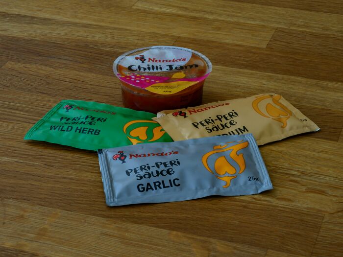 A collection of Nando's peri-peri sauces and chili jam, an absurd and hilarious firsthand sight.