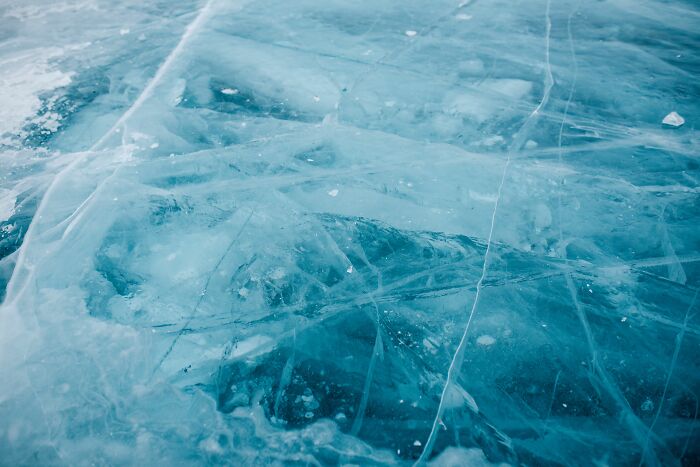Close-up of translucent blue ice with cracks and bubbles, an absurd and hilarious firsthand texture.