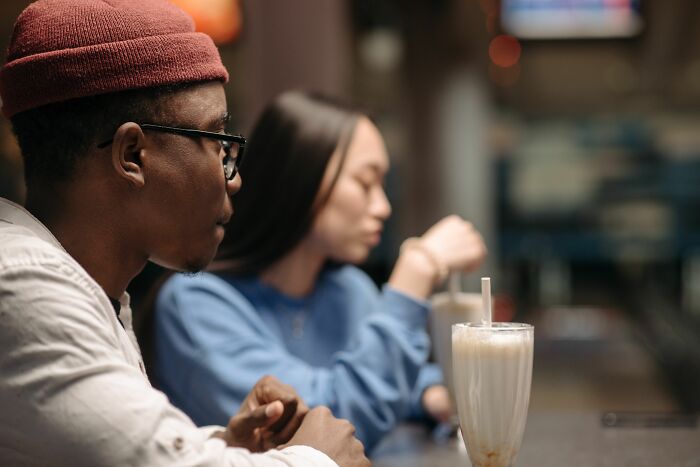 Two individuals sit at a counter, enjoying beverages. A firsthand witnessed scene of absurd and hilarious moments.