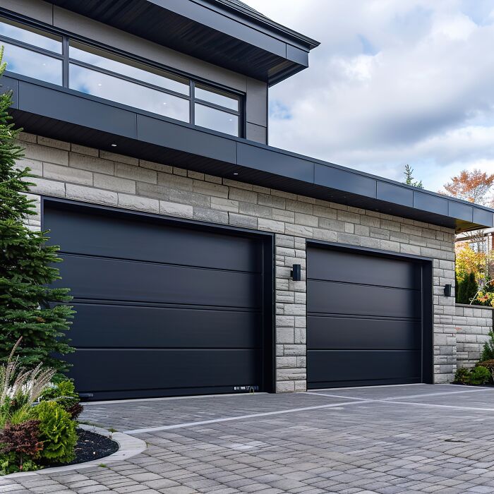 Modern house with two black garage doors and stone facade, unrelated to pet owners or vet bills.