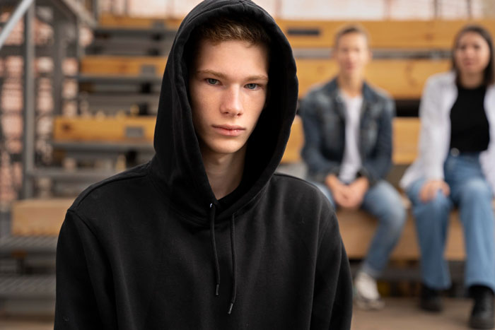 A teen in a black hoodie looking somber, representing the violent fight with sister that cost him his family.