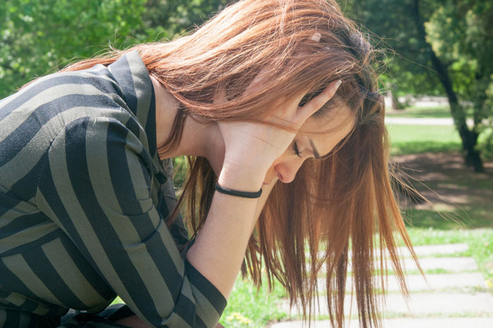 A distressed woman holding her head, reflecting the emotional cost of a violent fight with her sister.