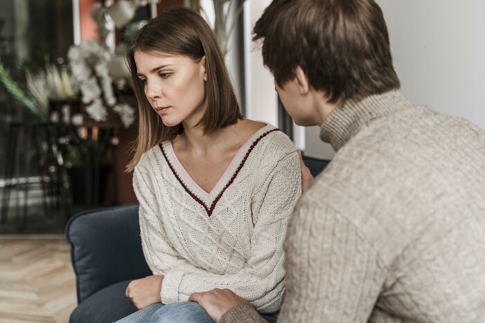 A woman looking down sadly while a man comforts her, highlighting common relationship red flags and mental health concerns.