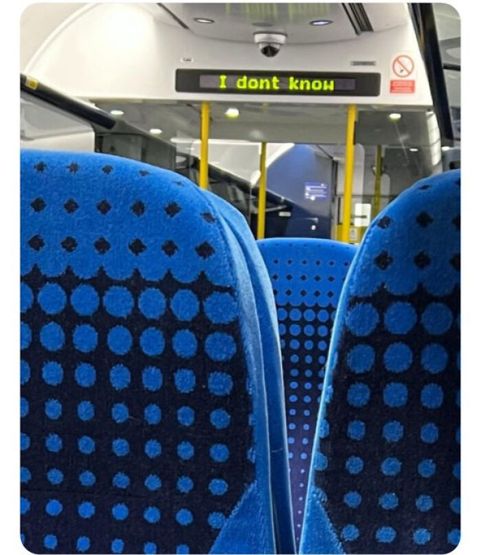 Interior of a bus with blue seats, and a digital sign saying 'I don't know', showcasing British humor.