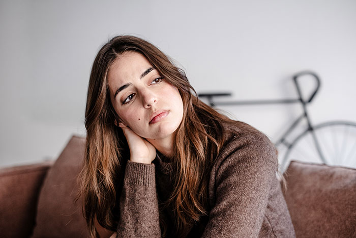 A woman looking contemplatively, illustrating an awkward moment of people sharing too much. A woman looking contemplatively, illustrating an awkward moment of people sharing too much.