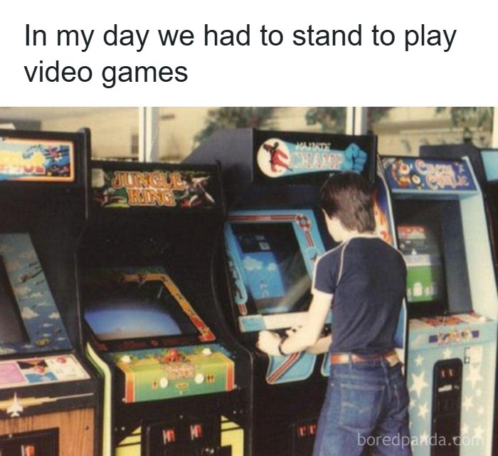 A person playing an arcade video game, standing at the machine, a classic 80s activity.