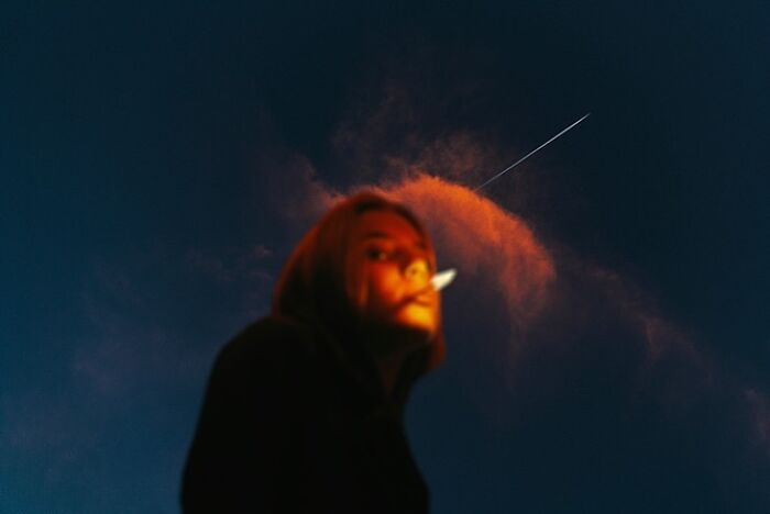 Oliver Takáč creates cinematic portraits, with a blurry image of a person smoking against an orange and blue sky.