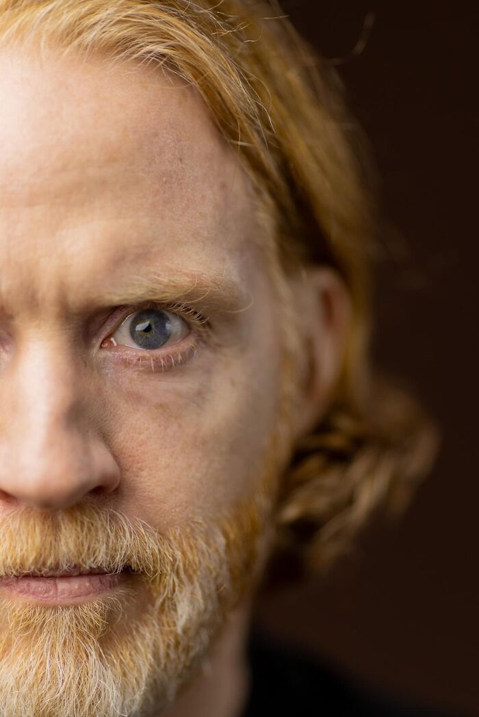 Close-up of a natural redhead man with a beard, blue eyes, focusing on the global portrait project.