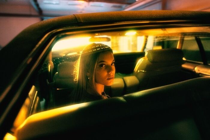 Oliver Takáč's cinematic portraits include a woman looking back from inside a car, illuminated by neon lights.