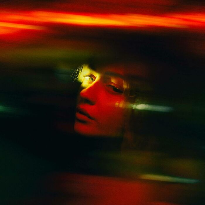 Oliver Takáč cinematic portrait of a woman's profile, illuminated by red and yellow neon lights with motion blur.