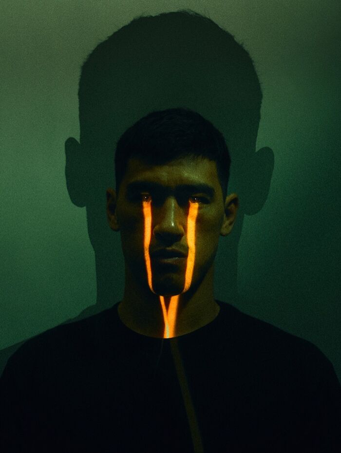 A man with bright orange neon lights reflecting on his face, creating a cinematic portrait.