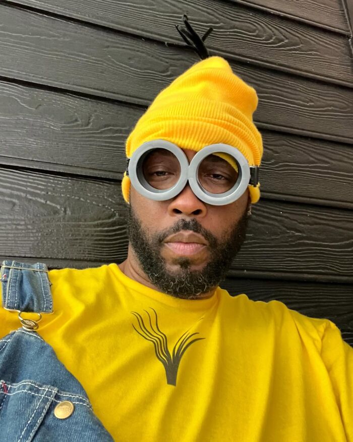 Man dressed as a Minion, a popular character, with yellow beanie, overalls, and goggles.