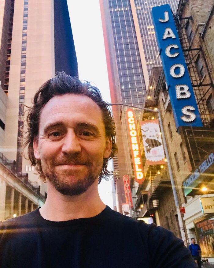 Tom Hiddleston smiles in a selfie on a city street, reflecting on what dating a celebrity is actually like.