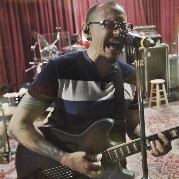 A male celebrity musician passionately singing into a microphone and playing an electric guitar, showing what dating a celebrity is like.
