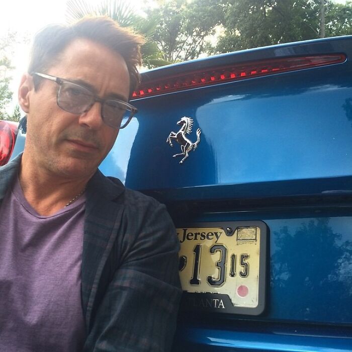 Robert Downey Jr. posing with a blue Ferrari, revealing what dating a celebrity is like.