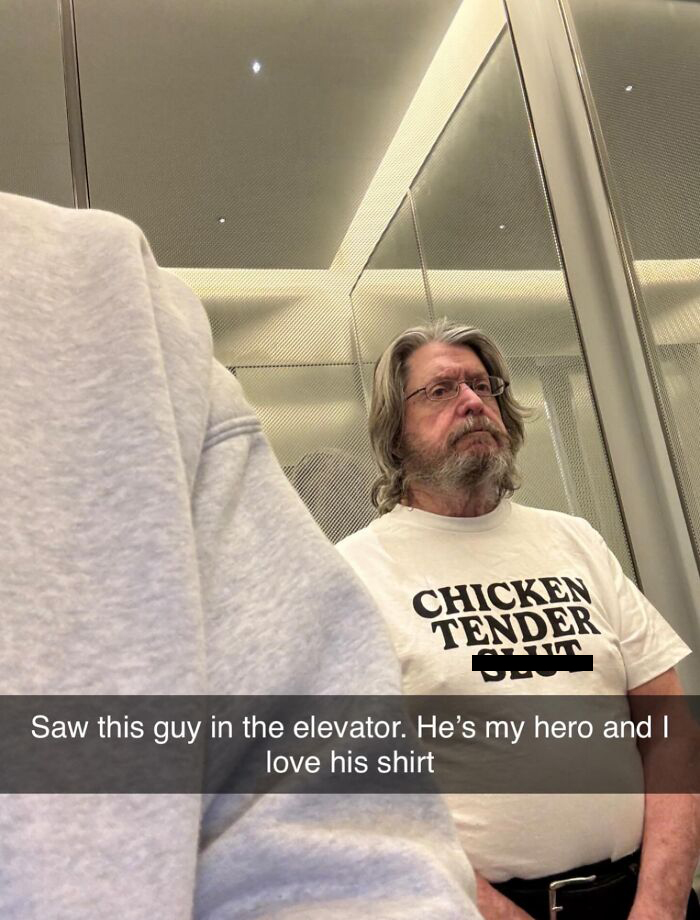 A man in an elevator wearing an unhinged T-shirts that says CHICKEN TENDER S**T, brilliant and bizarre.