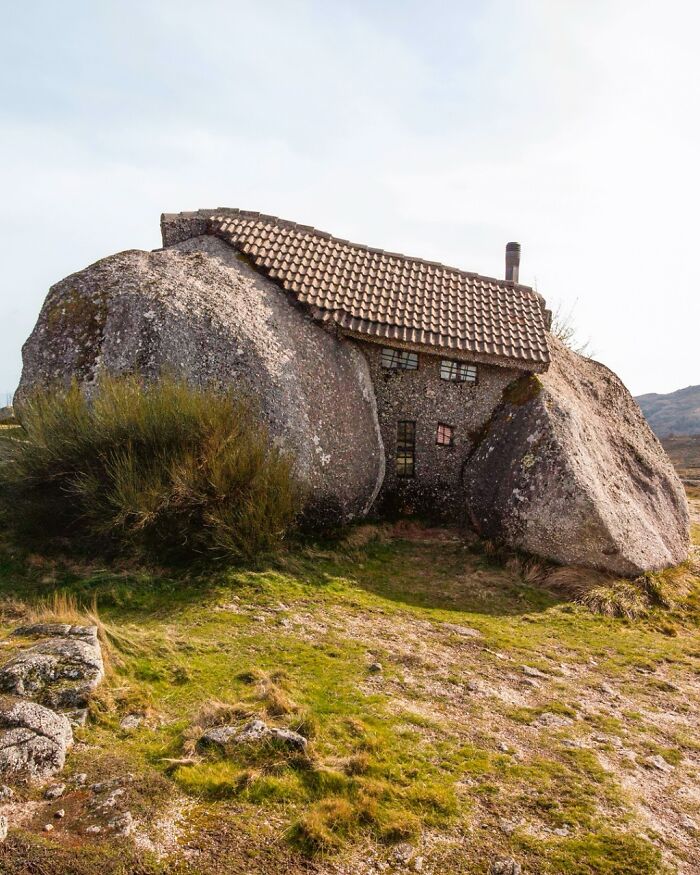 A brilliant and beautiful design of a house built into large rocks, blending with the natural landscape.