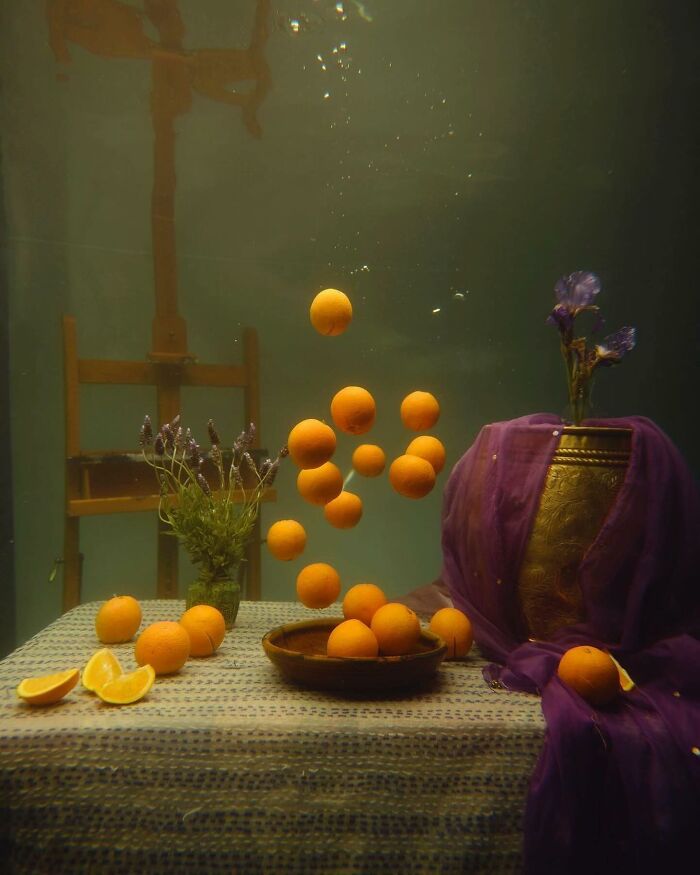 Brilliant designs: An ethereal underwater still life featuring floating oranges, flowers, and an easel, highlighting beautiful designs.