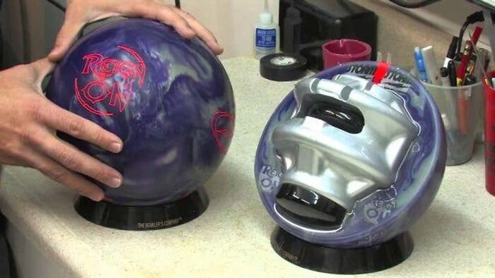Two bowling balls, one intact and one cut in half, revealing the internal core of the object.