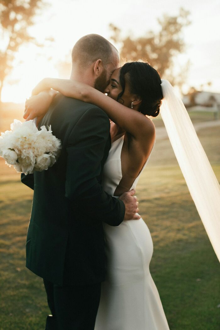 A newly married couple embraces in a field with the sunset behind them, illustrating truths about being married.