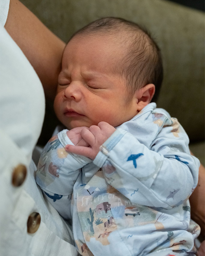 A close-up of JD Vance newborn son, eyes scrunched shut, resting on an arm, wearing a patterned onesie. Critics noted something. A close-up of JD Vance newborn son, eyes scrunched shut, resting on an arm, wearing a patterned onesie. Critics noted something.
