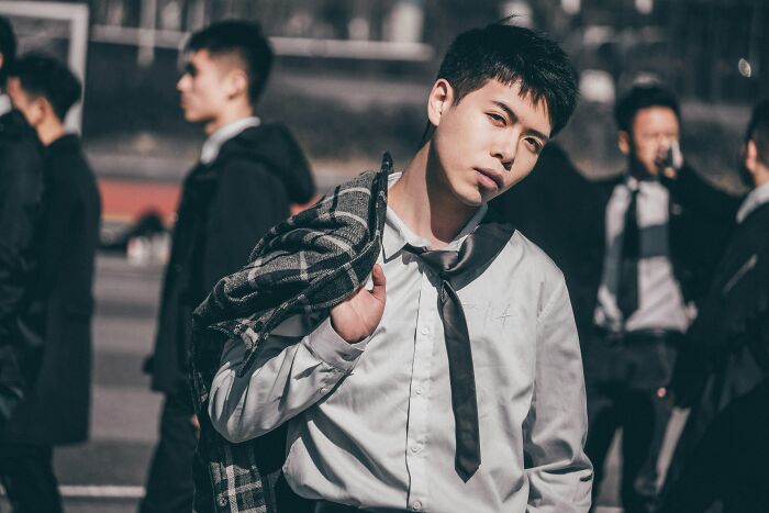 A stylish young man with a plaid jacket over his shoulder, delivering sick burns with his gaze.