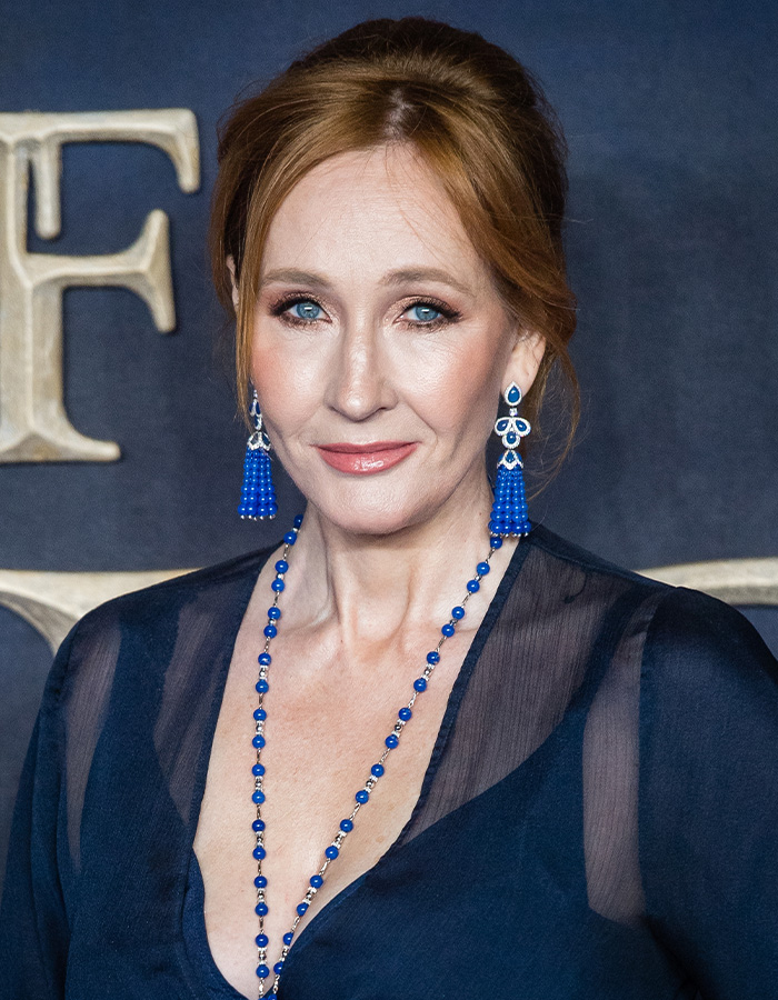 J.K. Rowling in a dark blue dress and earrings, facing accusations for controversial opinions. J.K. Rowling in a dark blue dress and earrings, facing accusations for controversial opinions.