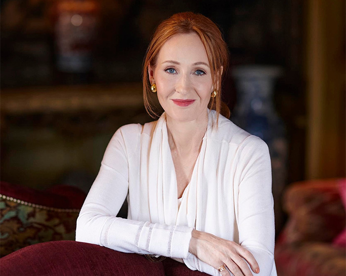 JK Rowling, author, in a white cardigan, looks directly at the camera, discussing transgender surgery.