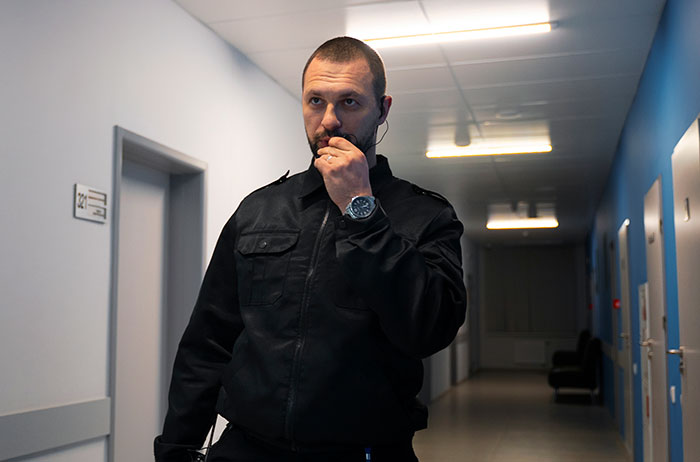 A security guard in a hallway speaking into a radio, representing various paid jobs.