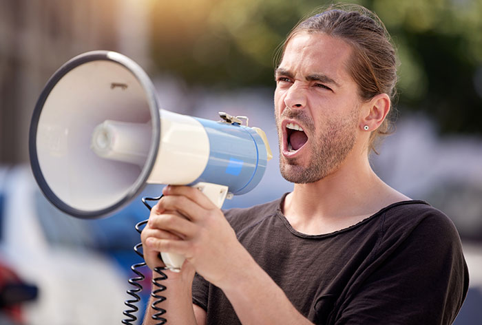 A man yelling into a megaphone, showing an example of one of the weird jobs that exist.