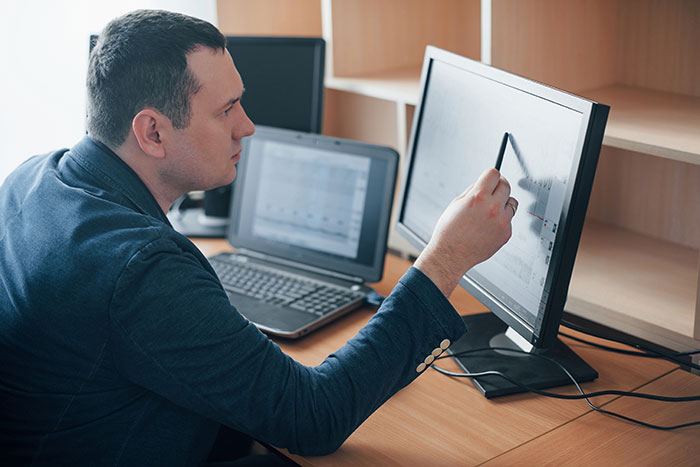 A man pointing at a computer screen, engaged in one of the many weird jobs people get paid to do.