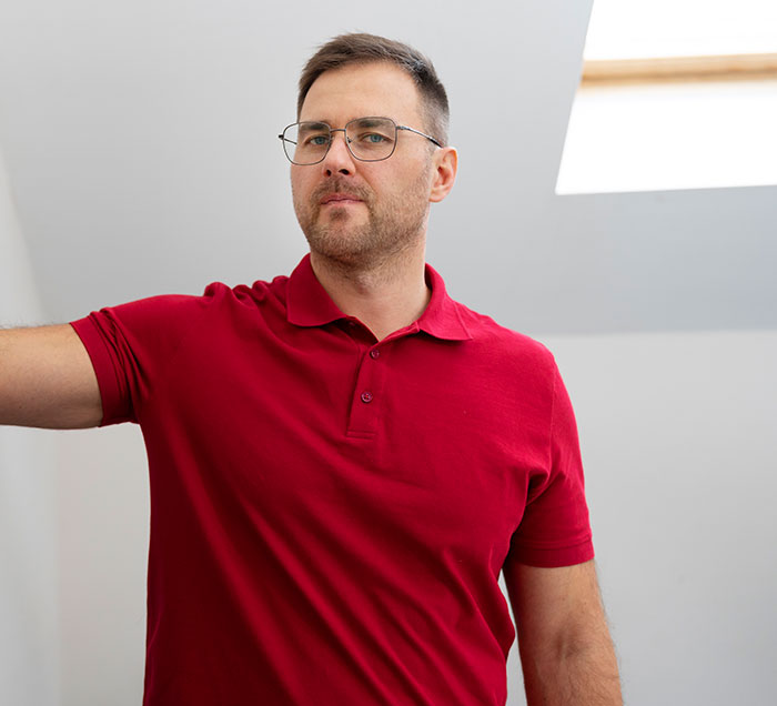 A man in a red polo shirt, wearing glasses, looks directly at the camera. He could be doing one of the weird jobs mentioned.