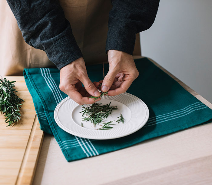 Hands meticulously picking rosemary leaves for a dish, highlighting weird jobs.