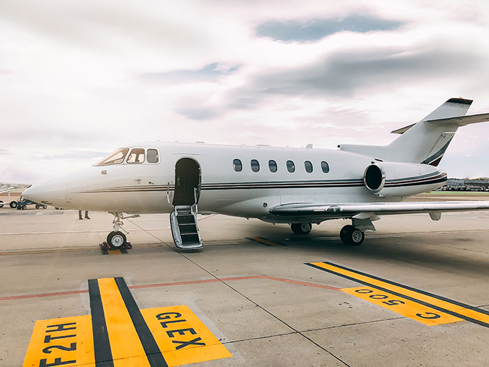 A sleek white private jet parked on an airfield with its door open, symbolizing luxury and some weird jobs.